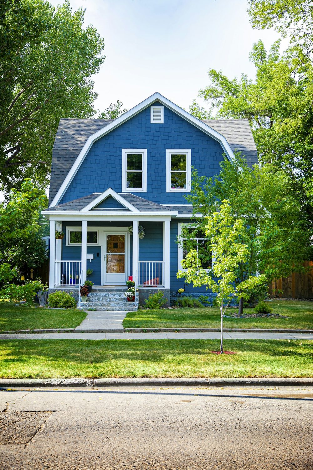 A welcoming blue two-story home with a front porch on a sunny day